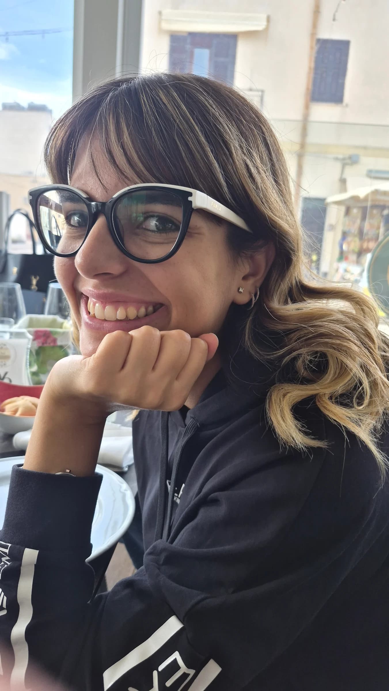 The practitioner's supplied portrait: a smiling woman with dark-framed glasses, seen close-up in a candid moment.